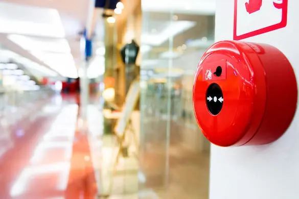 Red fire alarm installed in a large building hallway for enhanced fire detection and emergency alert system